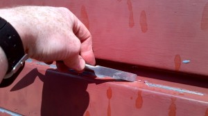 Scraping loose paint from garage door